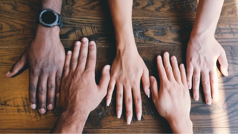 close up of hands on a table, hands are of people of varied ethnicities
